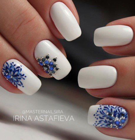 White nails with blue rhinestone.