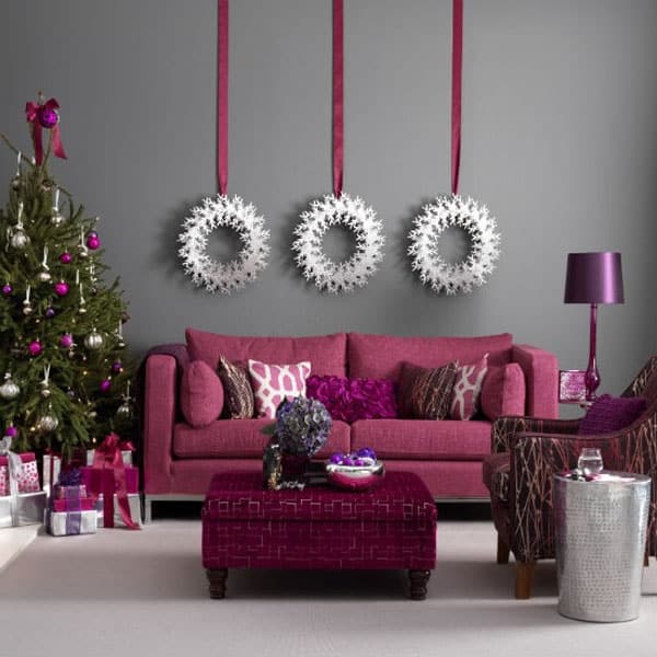 Modish pink living room decor with snowflakes wreath and Christmas tree decorated with silver, pink & purple ornaments.