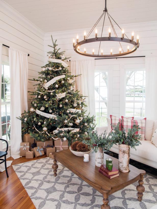 White & silver Christmas tree decor, plaid pillows with chandelier in living room.