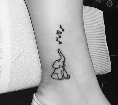 Chic baby elephant tattoo withmusic notes.