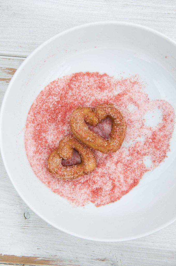 Heart-shaped churros coated in strawberry sugar.