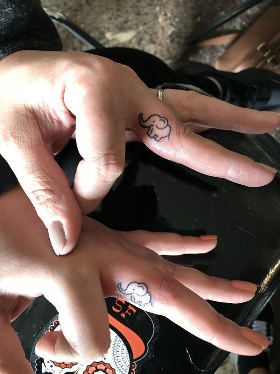 Mother daughter matching elephant finger tattoo.