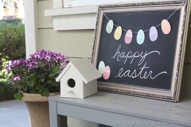 Chalk board is decorated with paper egg garland.