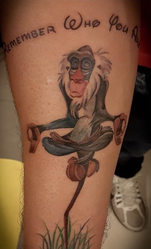 Colorful meditating monkey with a quote tattoo on forearm.
