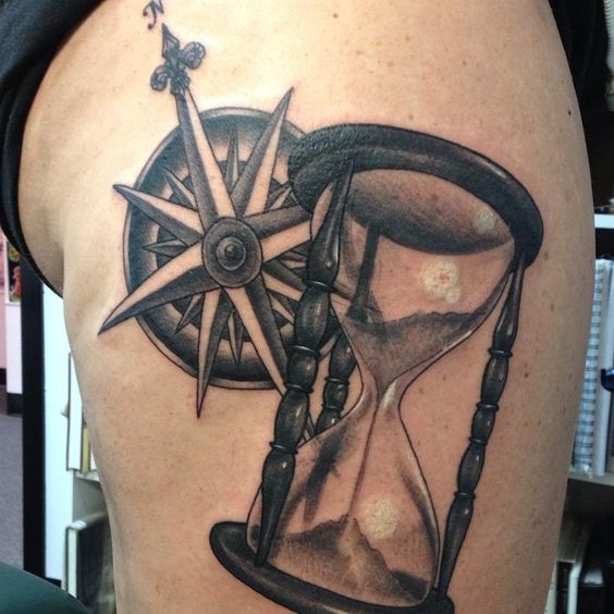 Compass with hourglass thigh tattoo.