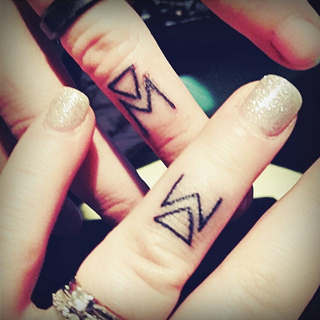 Graceful matching initial ring finger tattoos.