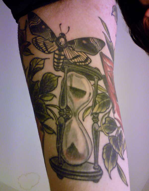 Natural touch hourglass tattoo covered with leaves.