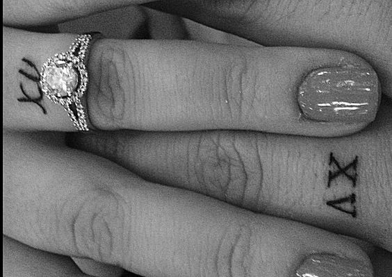Wedding date in roman numerals tattooed on ring fingers.