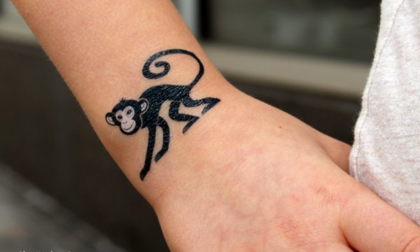 Wonderful black monkey tattoo on wrist.